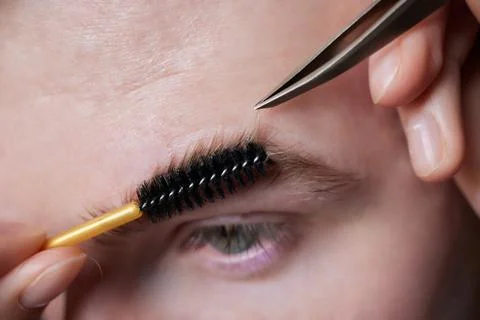 Professional barber doing threading procedure and correcting shape of eyebrows Stock Photos