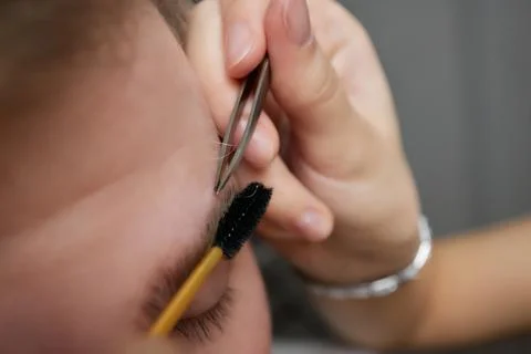 Professional barber doing threading procedure and correcting shape of eyebrows Stock Photos