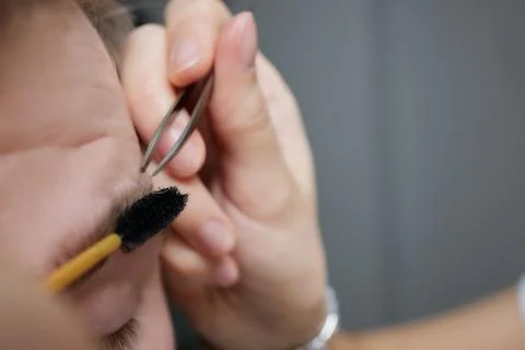Professional barber doing threading procedure and correcting shape of eyebrows Stock Photos