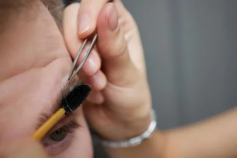 Professional barber doing threading procedure and correcting shape of eyebrows Stock Photos