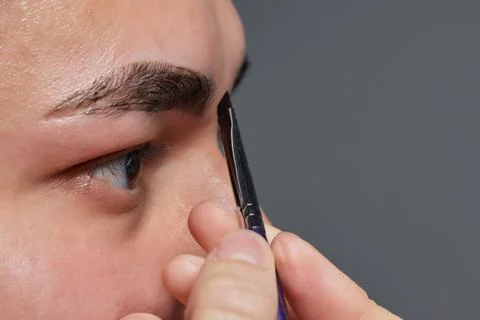 Professional barber doing threading procedure and correcting shape of eyebrows Stock Photos