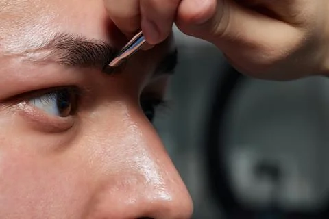 Professional barber doing threading procedure and correcting shape of eyebrows Stock Photos