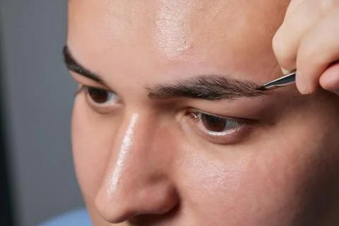 Professional barber doing threading procedure and correcting shape of eyebrows Stock Photos