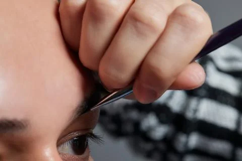 Professional barber doing threading procedure and correcting shape of eyebrows Stock Photos