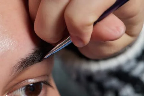 Professional barber doing threading procedure and correcting shape of eyebrows Stock Photos