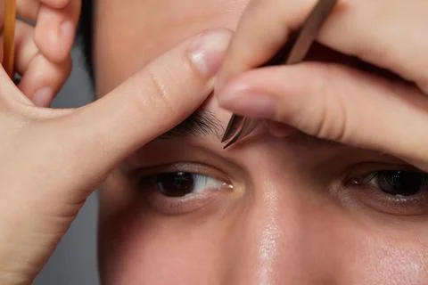 Professional barber doing threading procedure and correcting shape of eyebrows Stock Photos