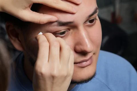 Professional barber doing threading procedure and correcting shape of eyebrows Stock Photos