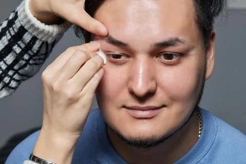 Professional barber doing threading procedure and correcting shape of eyebrows Stock Photos