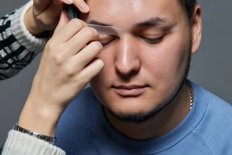 Professional barber doing threading procedure and correcting shape of eyebrows Stock Photos