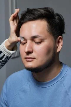Professional barber doing threading procedure and correcting shape of eyebrows Stock Photos