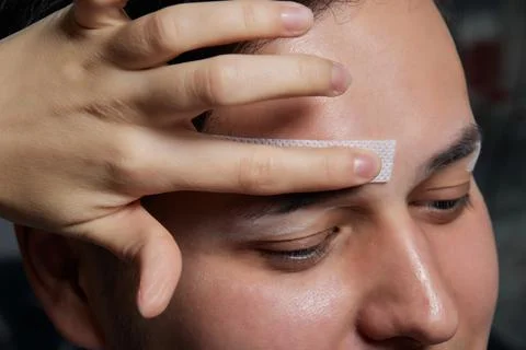 Professional barber doing threading procedure and correcting shape of eyebrows Stock Photos
