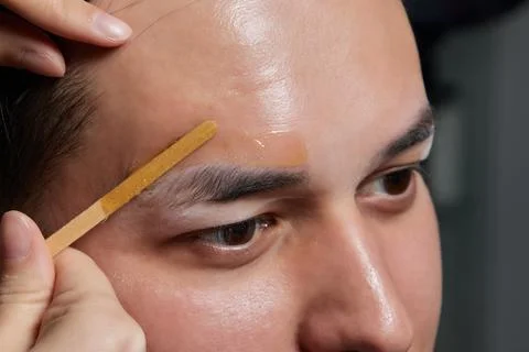Professional barber doing threading procedure and correcting shape of eyebrows Stock Photos