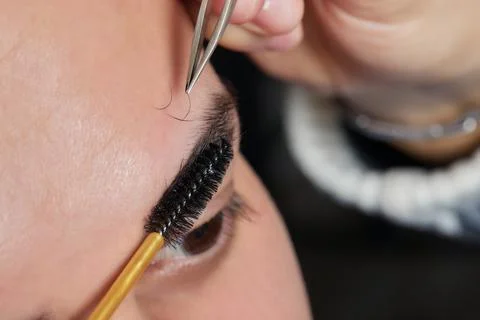 Professional barber doing threading procedure and correcting shape of eyebrows Stock Photos