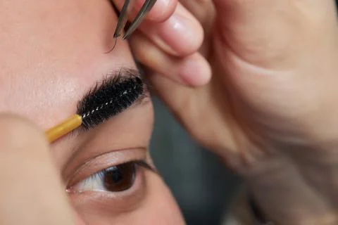 Professional barber doing threading procedure and correcting shape of eyebrows Stock Photos