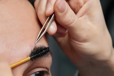 Professional barber doing threading procedure and correcting shape of eyebrows Stock Photos