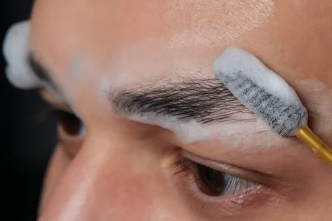 Professional barber doing threading procedure and correcting shape of eyebrows Stock Photos