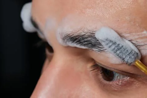 Professional barber doing threading procedure and correcting shape of eyebrows Stock Photos