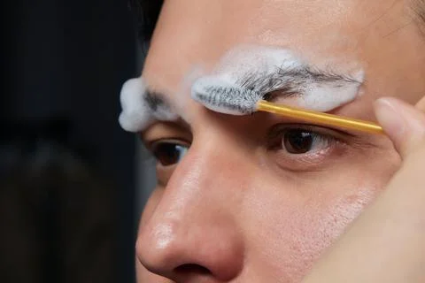 Professional barber doing threading procedure and correcting shape of eyebrows Stock Photos