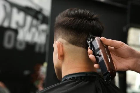 Professional barber making stylish haircut in salon, closeup Stock Photos