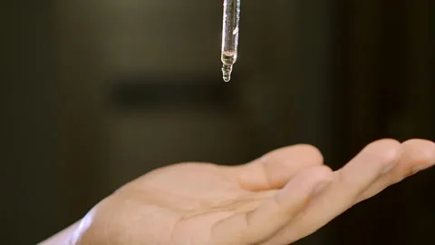 Professional barber transparent liquid drips on man hand Stockbeeldmateriaal 142998309