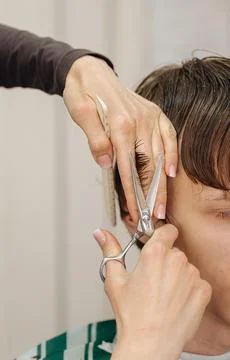 A professional barber using scissors and a comb to cut a client's hair Stock Photos