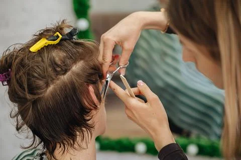 A professional barber using scissors and a comb to cut a client's hair Stock Photos