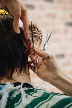 A professional barber using scissors and a comb to cut a client's hair Stock Photos