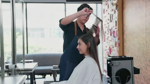 Professional barbers use scissors to trim the ends of long-haired female clie 스톡 동영상 153958890