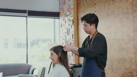 Professional barbers use scissors to trim the ends of long-haired female clie Stock Footage 153959371