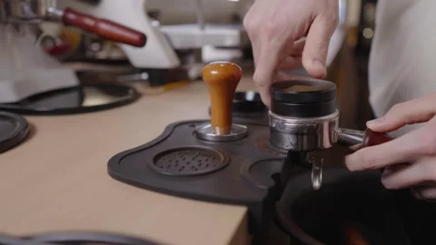 Professional barista hands using coffee distributor and leveler tool to prepare Stock Footage 328983996