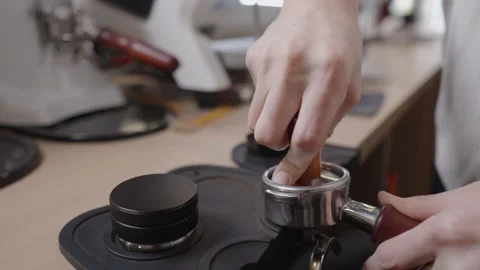 Professional barista hands using tamper to press freshly ground coffee into a Stock Footage 328984031