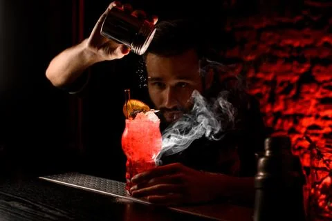 Professional bartender adding sugar powder to decorate glass with cocktail Fotos Stock
