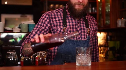 Professional bartender with beard and tattoos pouring cherry juice drink in Stock Footage 103734351