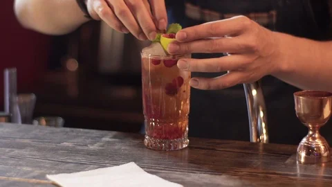 Professional bartender decorating cocktail with lime, raspberry and mint Stock Footage 96146635