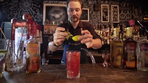 Professional bartender decorating cocktail with lime, raspberry and mint Video stock 96147770
