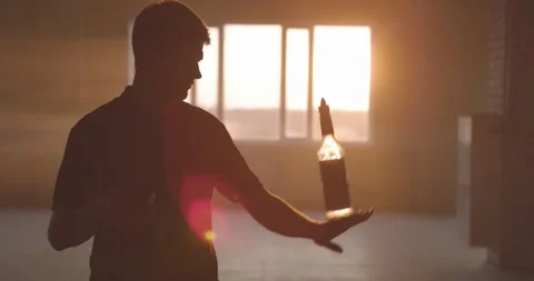 Professional bartender juggles bottles. The bartender is practice in hall at Stock Footage 154358562