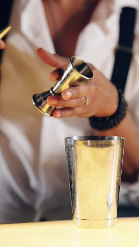 Professional bartender pouring liquor from a jigger into a cocktail shaker Stock Footage 334573883