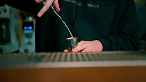A professional bartender pours alcohol into a measuring cup The process of Stock Footage 240439211