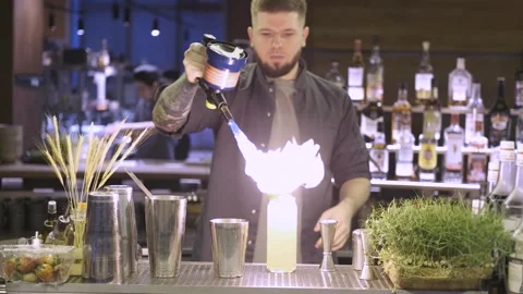 A professional bartender in a restaurant ignites a cocktail with a burner Stock Footage 247029535