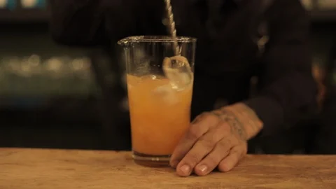 Professional Bartender Stirring Orange Drink with Bar Spoon Stock Footage 129782054
