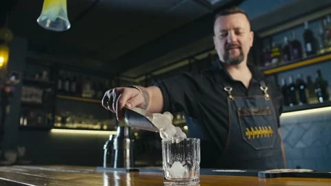 A professional bartender throws ice into a glass. Cold alcoholic cocktails Stock Footage 232372659