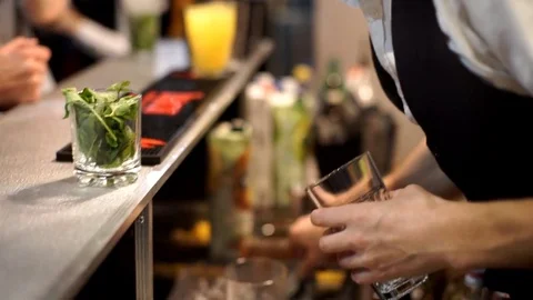 Professional bartender at work in bar mixing ice in glass for drink. Stock Footage