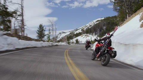 Professional bikers carrying skis while riding motorcycle on mountain pass Stock Footage 116743704