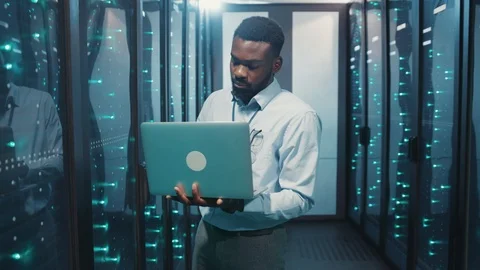 Professional black server engineer running tests on laptop computer inspecting Stock Footage 119082070