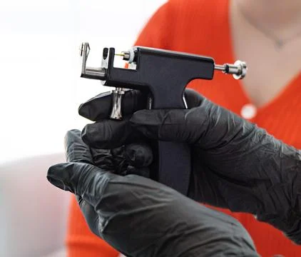 Professional body piercing instruments: piercing gun and earring. Stock Photos
