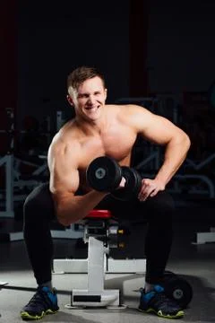 Professional bodybuilder do exercises for biceps sitting on the bench, with Stock Photos