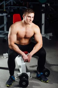 Professional bodybuilder sitting on the bench, resting between exercises with Stock Photos