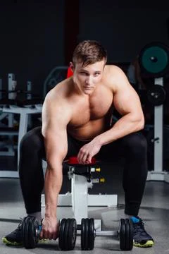 Professional bodybuilder sitting on the bench, resting between exercises with Stock Photos