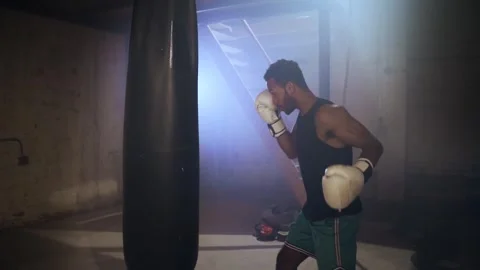Professional boxer training with a boxing bag in dark gym in slow motion Stock Footage 242783751