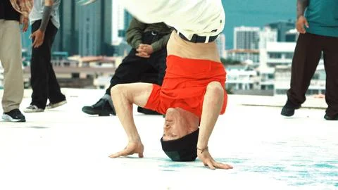 Professional break dancer doing head spin at roof top with city view. Hiphop. Stock Photos